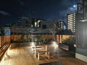 a wooden deck with a bench on a rooftop at night at GUEST HOUSE SaKURa in Tokyo