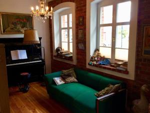 a living room with a green couch and a piano at Historical holiday home in Mielenko 400 m from the sea in Mielenko
