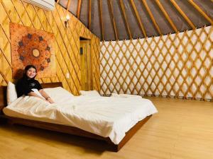 a woman sitting on a bed in a yurt at Tanyoli Resort in Phan Rang