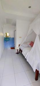 um quarto branco com uma cama e uma mesa em Bintang Bungalow Tour & Travel em Kelimutu