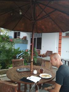 a man sitting at a table under an umbrella at Bintang Bungalow Tour & Travel in Kelimutu