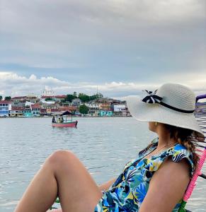Una mujer con sombrero sentada en un barco en el agua en Hotel San Miguel en Flores