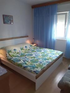 a bedroom with a bed with a floral blanket on it at Apartments with parking space Novi Vinodolski - 2416 in Novi Vinodolski