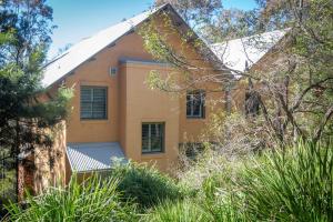 una casa amarilla con techo blanco y algunos árboles en Villa Legato, en Pokolbin