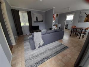 a living room with a gray couch and a table at Kalgan River Chalets and Caravan Park in Kalgan