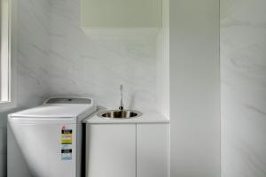 a white kitchen with a sink on top of a refrigerator at East Tempy House and Bungalow in Port Fairy