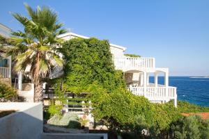 a white house with a palm tree and the ocean at Apartments by the sea Milna, Vis - 2461 in Rukavac