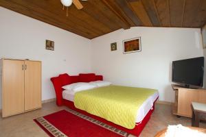 a bedroom with a bed and a flat screen tv at Apartments by the sea Milna, Vis - 2461 in Rukavac