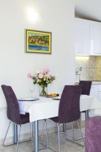 a white table with chairs and a vase of flowers at Apartment Vis 2428c in Vis