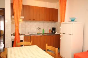 a kitchen with a table and a white refrigerator at Apartments and rooms with parking space Mali Losinj (Losinj) - 2486 in Mali Lošinj