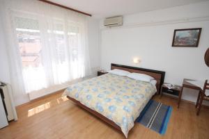 a bedroom with a bed and a table and window at Apartments and rooms with parking space Mali Losinj (Losinj) - 2486 in Mali Lošinj