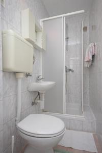 a white bathroom with a toilet and a shower at Apartments and rooms with parking space Mali Losinj (Losinj) - 2486 in Mali Lošinj