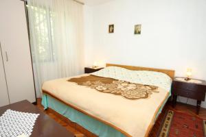 a bedroom with a bed and a table and a window at Apartments by the sea Mali Losinj (Losinj) - 2493 in Mali Lošinj