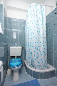 a bathroom with a blue toilet and a shower curtain at Apartments with a parking space Mali Losinj (Losinj) - 2507 in Mali Lošinj