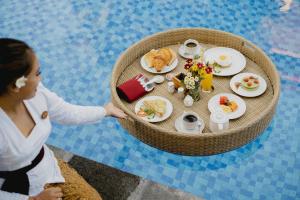 een vrouw reikt naar een tafel met eten bij Gora House Bali in Ubud