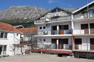 a white apartment building with a mountain in the background at Double Room Podaca 2613a in Podaca