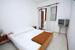 a white bedroom with a bed and a tv at Apartments and rooms with WiFi Podaca, Makarska - 2613 in Podaca