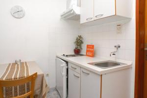 uma pequena cozinha branca com um lavatório e uma mesa em Apartment Podaca 2621a em Podaca