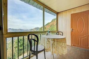 丹瑙提的住宿－GREEN VALLEY RESORT PVT LTD，阳台配有桌椅和大窗户。