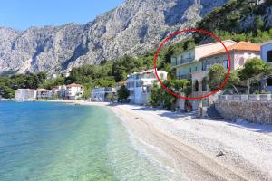 a red circle on a beach next to a building at Apartments by the sea Drasnice, Makarska - 2644 in Drasnice