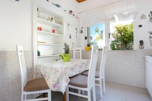 Biała kuchnia ze stołem i krzesłami oraz oknem w obiekcie Apartments by the sea Drasnice, Makarska - 2644 w mieście Drašnice