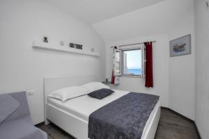 a white bedroom with a bed and a window at Apartments by the sea Drasnice, Makarska - 2581 in Drasnice