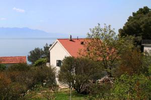 ein weißes Haus mit rotem Dach neben dem Wasser in der Unterkunft Apartments by the sea Zaostrog, Makarska - 2625 in Zaostrog