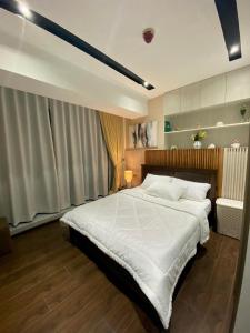 una camera da letto con un grande letto con lenzuola bianche di Aeon Towers Executive Suite 2BR 18th floor a Davao