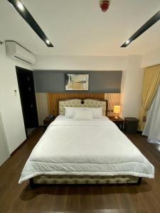 una camera da letto con un grande letto con lenzuola e cuscini bianchi di Aeon Towers Executive Suite 2BR 18th floor a Davao