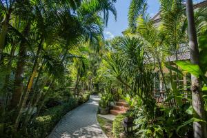 a path through a garden with palm trees at Laksasubha Hua Hin in Hua Hin