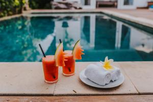 dos bebidas sentadas en una mesa junto a una piscina en Villa Escape, en Nusa Lembongan