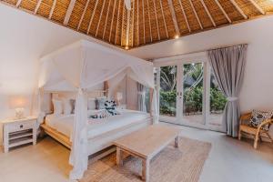 1 dormitorio con cama blanca con dosel y mesa en Villa Escape, en Nusa Lembongan