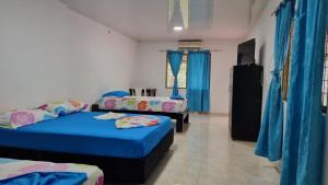 Tauramena的住宿－Finca Ecoturística Canaguaros，一间设有两张床和蓝色窗帘的房间
