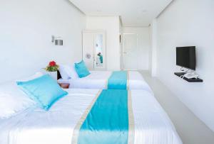 Habitación blanca con 2 camas y TV. en RedDoorz at PWL Exclusive Resort Cebu en Carmen