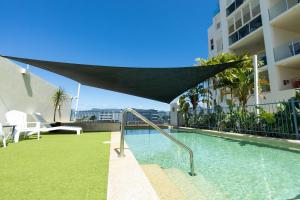 a swimming pool with a hammock on the side of a building at Afternoon Delight in Cairns