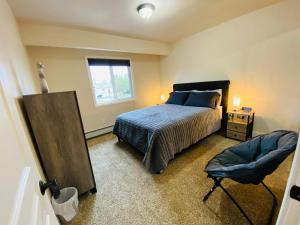 a bedroom with a bed and a chair and a window at Beautiful 2 bedroom 1 bath apartment with private garage in Anchorage