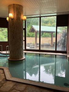 a swimming pool with a column and windows at 田沢湖水沢温泉郷セルリアンリゾートAoni in Senboku