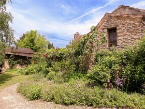 een oud stenen huis met bloemen ervoor bij Family house in a fairytale hamlet with a beautiful swimming pool in Falcou