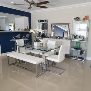 uma sala de jantar com uma mesa de vidro e cadeiras brancas em Casa806 Men Only Guest House em Fort Lauderdale