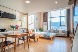 July Apartment في هانغتشو: مطبخ وغرفة معيشة مع أريكة وطاولة