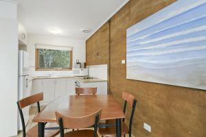 eine Küche mit einem Tisch und Stühlen sowie ein Gemälde an der Wand in der Unterkunft Split Point Cottages in Aireys Inlet