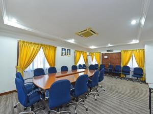 Super OYO Capital O 90434 Marmoris House في كوالا ترغكانو: قاعة اجتماعات مع طاولة خشبية وكراسي زرقاء