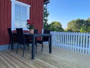 une table et des chaises noires sur une terrasse dans l'établissement Fogdarps B&B -Eget gästhus-, à Förslöv