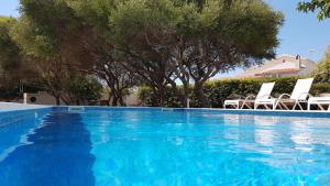 a blue swimming pool with chairs and trees at Starbal Apt in Es Castell +31 photos