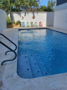 a swimming pool with blue water and colorful chairs at Sea breeze vacation lll en Condominio Verde mar in San Juan