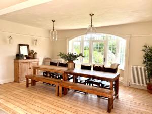 a dining room with a wooden table and benches at Highview House Norfolk Coast - seaviews, beach, hot tub in Mundesley