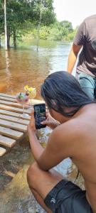 una mujer tomando una foto de un pájaro en el agua en Refúgio Samauma, en Manaus