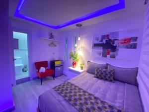 a purple bedroom with a bed and a red chair at Alegria Hostal in Santiago de los Caballeros