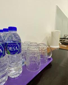 a group of water bottles and glasses on a purple tray at D' Anjung Inn in Tangkak
