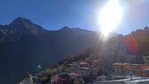 a view of a city with the sun shining on a mountain at Odyssey Stays Joshimath - Near Narsingh Temple in Joshīmath